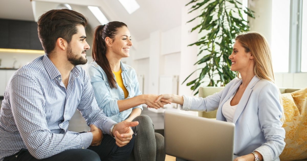 foto de una asesora inmobiliaria dando la mano a sus clientes