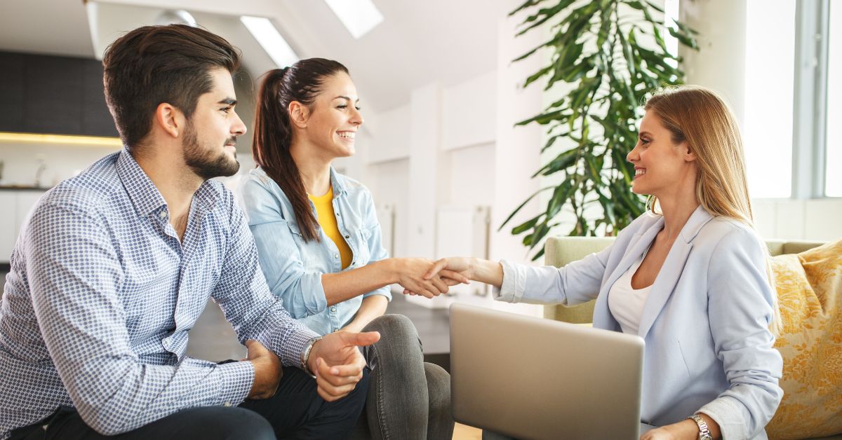 foto de una asesora inmobiliaria dando la mano a sus clientes